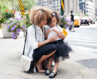 Photo of woman kneeling with a girl in her lap